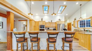 Una cocina amplia con armarios de madera, una isla central con taburetes altos y tragaluces.