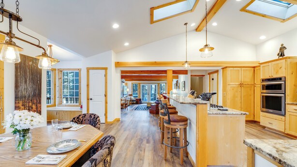 Una cocina amplia con armarios de madera, una isla central con taburetes de bar y un comedor con mesa dispuesta para cuatro.