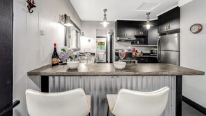 A modern kitchen with a central island, stainless steel appliances, and white bar stools. - 30-Day Min, Walking Distance to Downtown & Lake + Nearby Whitefish Mountain Resort! (Whitefish)