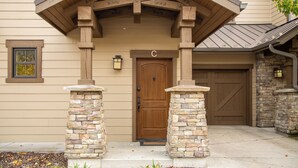 A house with a wooden front door, stone pillars, and a garage.