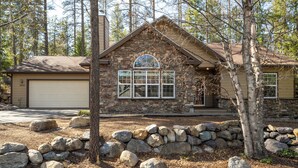 A stone house with a garage, surrounded by large rocks and trees. - 30-Day Min, Close to Downtown, Walk to Golf & Lake! (Whitefish)