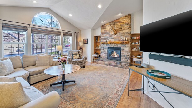 A spacious living room with a stone fireplace, comfortable seating, and a large flat-screen TV. - 30-Day Min, Close to Downtown, Walk to Golf & Lake! (Whitefish)