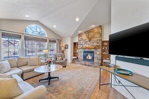 A spacious living room with a stone fireplace, comfortable seating, and a large flat-screen TV. - 30-Day Min, Close to Downtown, Walk to Golf & Lake! (Whitefish)