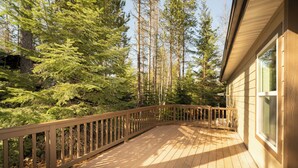 A wooden deck with a railing, surrounded by tall trees. - 30-Day Min, Close to Downtown, Walk to Golf & Lake! (Whitefish)