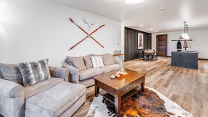 A modern living room with a sofa, coffee table, and a wall-mounted ski rack. - Hot Tub + Close to Downtown, Smith Fields and Whitefish Mountain Resort! (Whitefish)