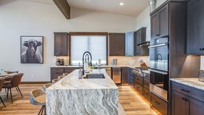 Una cocina moderna con armarios de madera oscura, una isla de mármol y electrodomésticos de acero inoxidable.