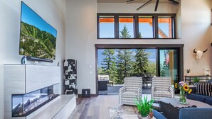 Una sala de estar moderna con un televisor grande, asientos cómodos y vistas al exterior.