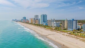 Un paisaje urbano costero con playa, edificios altos y cielo despejado.