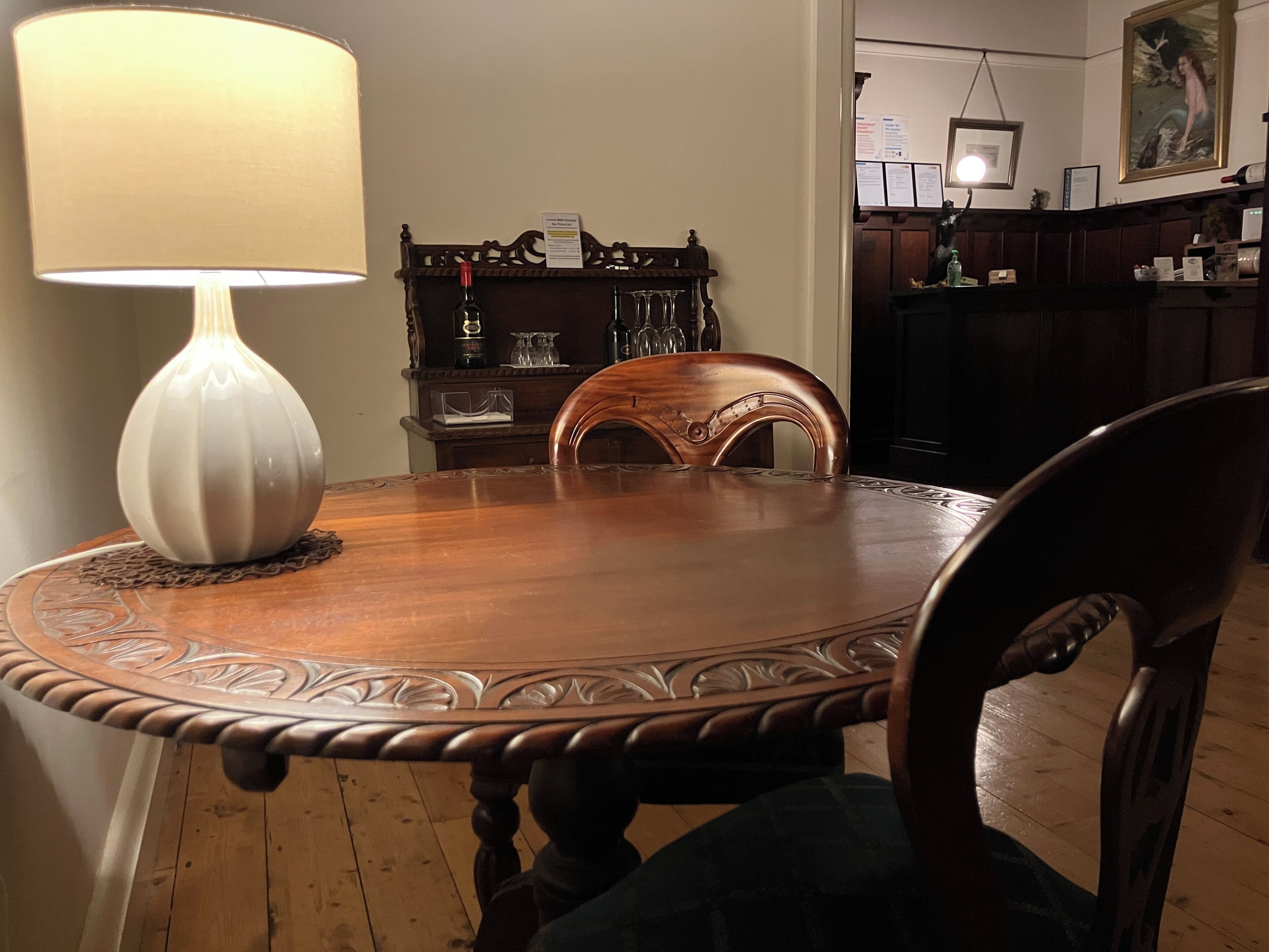 Uma mesa de jantar com uma luminária, cadeiras e chão de madeira.