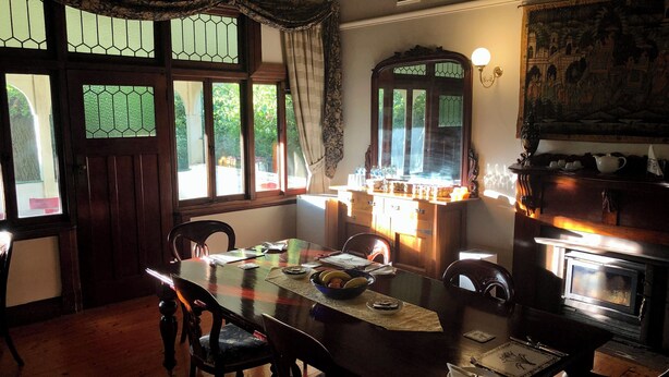 Un coin repas comprenant une table en bois, des chaises, une cheminée et une fenêtre avec des rideaux.