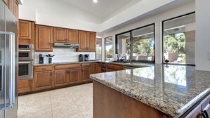 A modern kitchen with wooden cabinets, stainless steel appliances, and a granite countertop. - ScottsdaleStays 10BR-6BA Multimillion Acre Estate-Pool-SportCourts-SPECIAL DEALS (Phoenix)