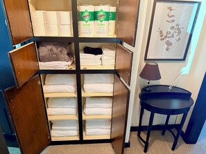 A storage unit with multiple shelves containing folded towels and paper products.