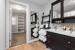 A bathroom with a dark vanity, a large mirror, and a towel rack. - Luxurious 1875 Home, King Suite + Central Location (Uniontown)