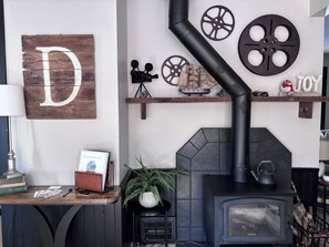 A cozy room with a fireplace, a wooden sign with a large letter 'D', and a shelf with decorative items.