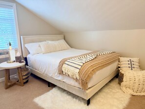 Une chambre à coucher avec un lit, une table de chevet, une lampe et une fenêtre avec des stores.