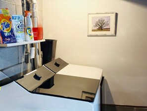 Een keuken met een vaatwasser, een spoelbak en een plank met schoonmaakmiddelen.