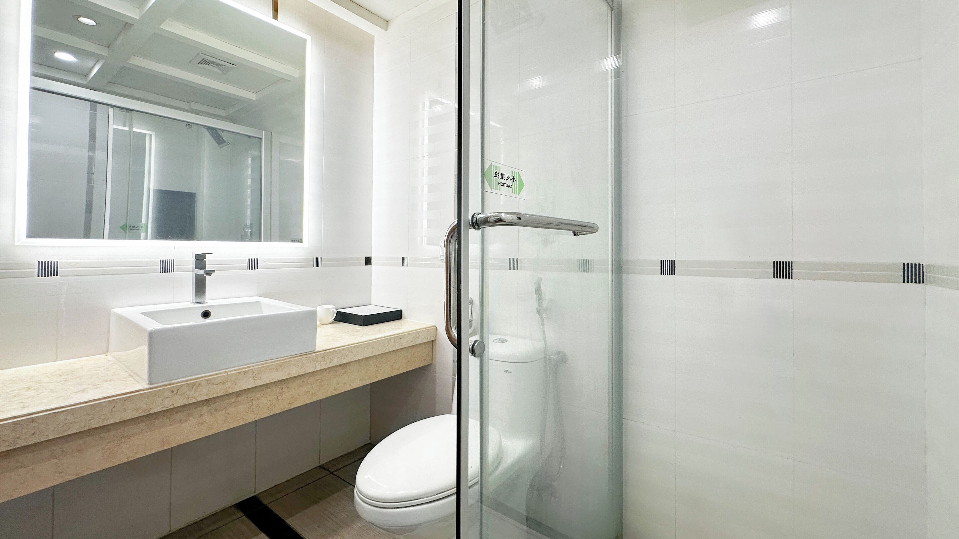 Een moderne badkamer met een douchecabine van glas, een wastafel met spiegel en een toilet.
