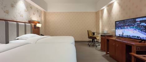 Una habitación de hotel con dos camas, un escritorio con televisor y una silla.