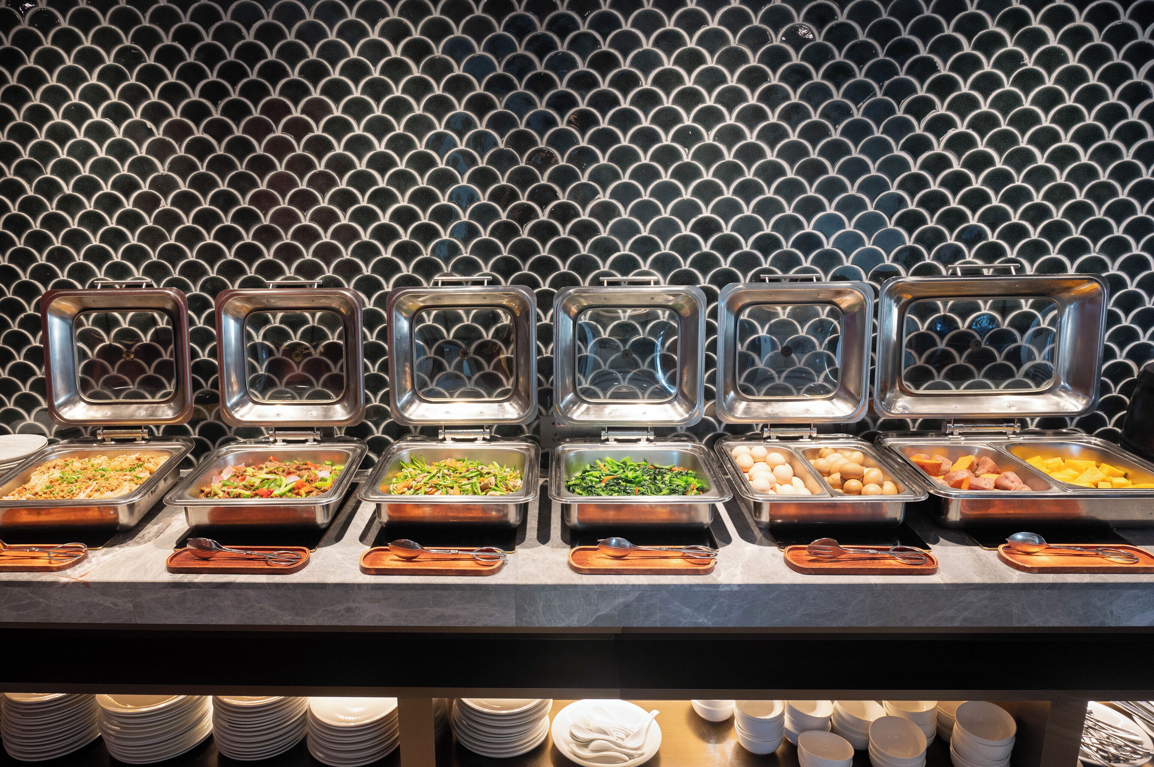 A buffet with multiple food stations, each with a metal container and a wooden serving tray.