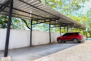 A covered parking area with a red SUV parked inside.