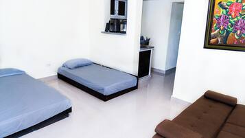 Una habitación con dos camas, una kitchenette y un cuadro en la pared.