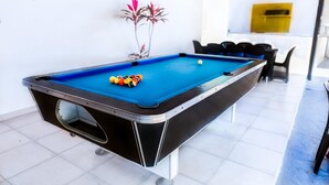 A pool table with balls, a chair, and a plant in a room with white walls and a tiled floor. - Villa Stephanie Your Perfect Getaway With Free Pool Table (La Vega)