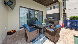 An outdoor patio with a glass-top table, wicker chairs, and a ceiling fan. - Liberty Bluff Dream | 5 bed, 5 bath | Private Pool | Golf Course Views (Kissimmee)