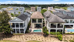 A residential area with houses featuring large windows, a swimming pool, and a well-maintained lawn. - Liberty Bluff Dream | 5 bed, 5 bath | Private Pool | Golf Course Views (Kissimmee)