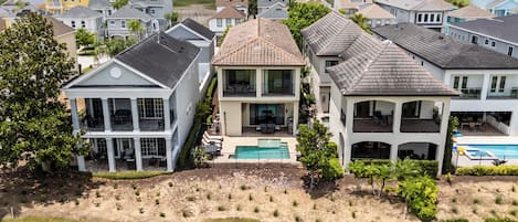 A residential area with houses featuring large windows, a swimming pool, and a well-maintained lawn.