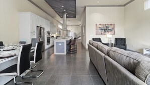 A modern kitchen with white cabinets, a stainless steel refrigerator, and a central island with bar stools. - Liberty Bluff Dream | 5 bed, 5 bath | Private Pool | Golf Course Views (Kissimmee)