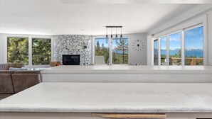 Ein modernes Wohnzimmer mit Kamin aus Stein, großen Fenstern und Blick ins Freie.