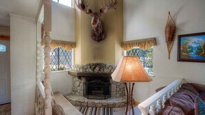 A cozy interior with a stone fireplace, a mounted deer head, and a cushioned seating area.