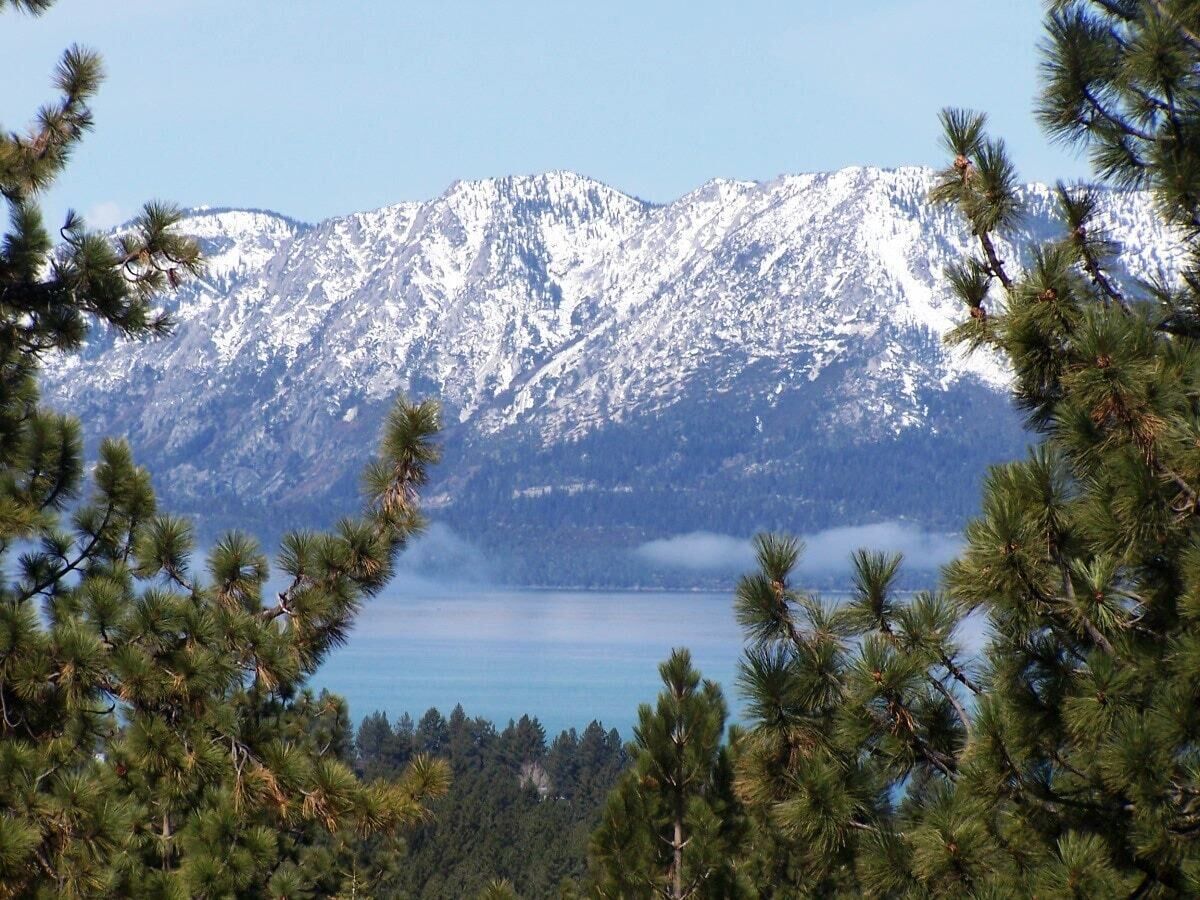 Cordillera con picos nevados y un cuerpo de agua en primer plano.