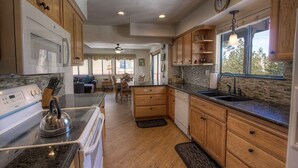 A kitchen with wooden cabinets, a microwave, stove, and a sink.