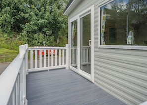 A covered deck with a white railing, a sliding glass door, and a view of a green landscape. - 2 Bedroom platinum unit with decking. (Longridge, Ribble Valley)