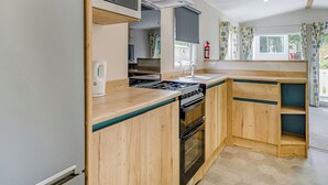A kitchenette with a microwave, stove, oven, and a coffee maker.