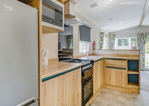 Una kitchenette equipada con microondas, estufa, horno y cafetera.