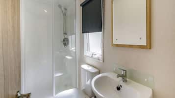 A modern bathroom with a glass-enclosed shower, a white toilet, a sink, and a mirror.