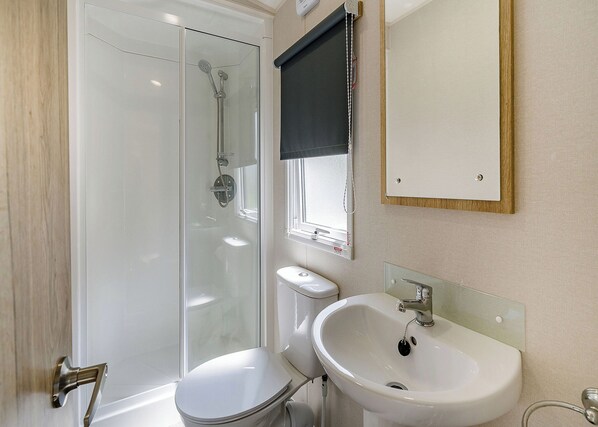 A modern bathroom with a glass-enclosed shower, a white toilet, a sink, and a mirror.