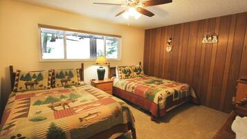 A bedroom with two beds, a ceiling fan, a window, and a wooden wall.