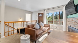 Un salon avec un canapé en cuir marron, une table à manger en bois et un escalier avec des rampes en bois.
