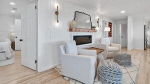 A modern living room with a fireplace, white walls, and wooden flooring. - "You are My Sunshine" Fully Renovated, 3 Bedroom, 2 Bathroom, Oceanfront Home (Holden Beach)
