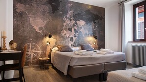 A modern bedroom with a large world map mural, a desk with a chair, and a bed with pillows and a blanket. - Room 'Stanza 2' with Shared Garden, Wi-Fi and Air Conditioning (Viggiù)