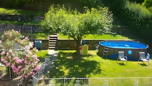 A backyard with a swimming pool, a small tree, and a fence. - Room 'Stanza 2' with Shared Garden, Wi-Fi and Air Conditioning (Viggiù)