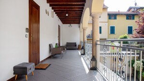 A balcony with a wooden ceiling, a sofa, and a small table. - Room 'Stanza 2' with Shared Garden, Wi-Fi and Air Conditioning (Viggiù)