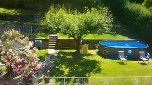 A backyard with a swimming pool, a small tree, and a fence.