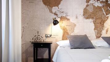 A bedroom with a world map wall, a bed with pillows, a nightstand, and a lamp.