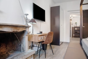 A modern room with a fireplace, a desk, a chair, a television, and a wardrobe.