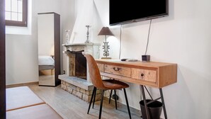 Quarto moderno com cama, escrivaninha de madeira, televisão e lareira.