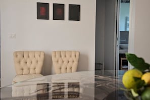 Una habitación con dos sillones tapizados, una mesa de cristal y tres cuadros en la pared.